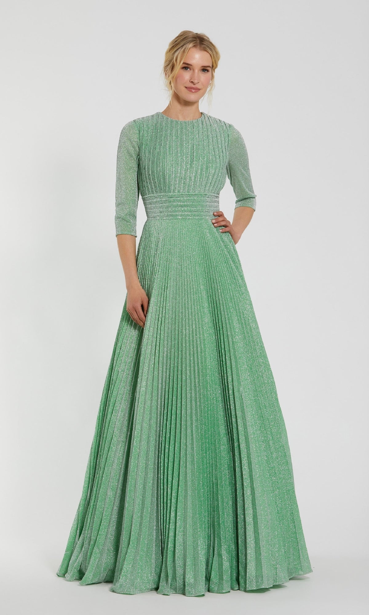 A woman wears the Mac Duggal 30775 Sage Long Pleated Formal Dress, featuring an A-line silhouette and three-quarter sleeves, standing against a plain white background.